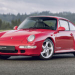 Red 911 993 air cooled car parked on a road with trees in background