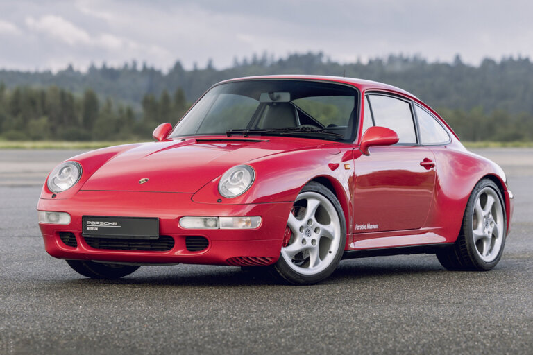 Red 911 993 air cooled car parked on a road with trees in background