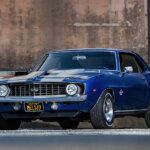 1969 blue camaro ss next to a warehouse