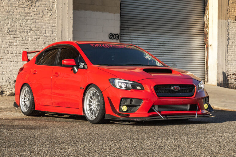 red Subaru WRX next to warehouse