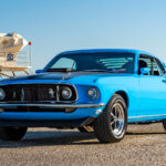 blue mustang mach 1 at a beach