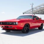 Red 74' Dodge in parking structure with blue sky in background