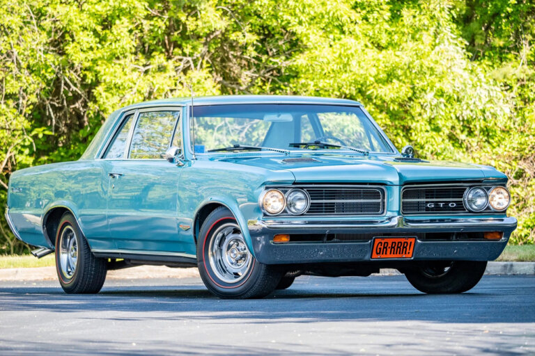 light blue Pontiac in front of trees