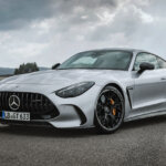 Silver Mercedes Benz AMG GT Coupe parked with cloudy sky behind it