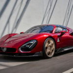 Red Alfa Romeo 33 Stradale driving on the street passing a white wall with shadows on it