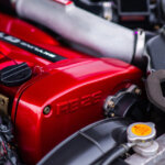 red valve cover with stamped writing RB26 on it next to tubes and pipes