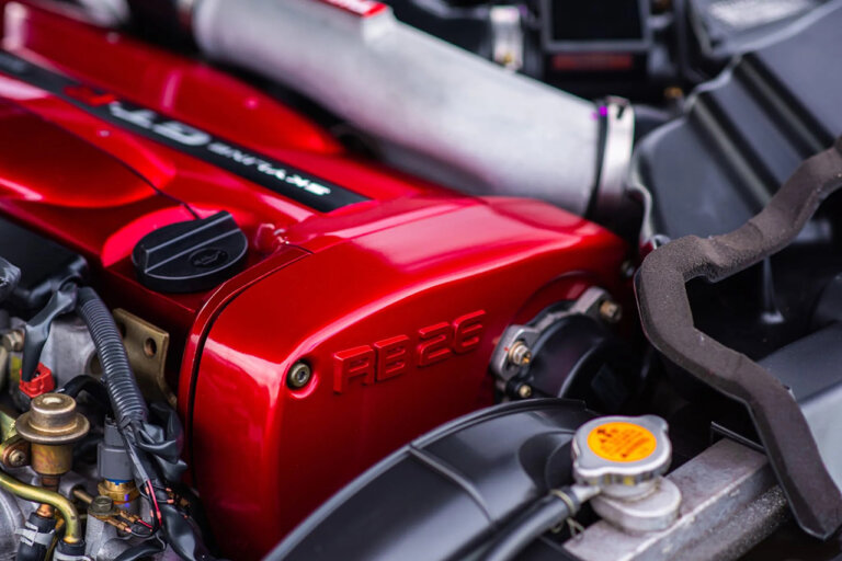 red valve cover with stamped writing RB26 on it next to tubes and pipes