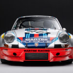 Martini Porsche parked in a dark room, black background and white floor
