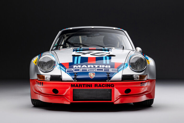 Martini Porsche parked in a dark room, black background and white floor