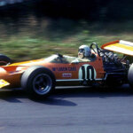bruce mclaren in an orange mclaren f1 car