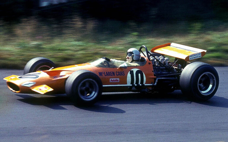 bruce mclaren in an orange mclaren f1 car