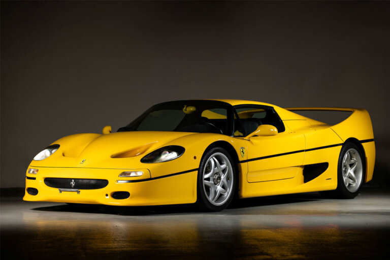 Yellow Ferrari F50 on dark background parked with lights on