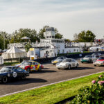 Several Porsche vehicles in racing liveries racing on a race track
