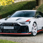 White with red trim Audi RS6 Avant GT parked in front of some green bushes