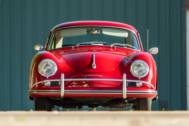 Red Porsche 356 parked in front of a green striped wall