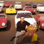 man sitting on a chair infront of a bunch of vehicles from red, to white, to yellow