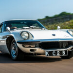 White Mazda car with an driving it on a freeway with blue sky and mountains