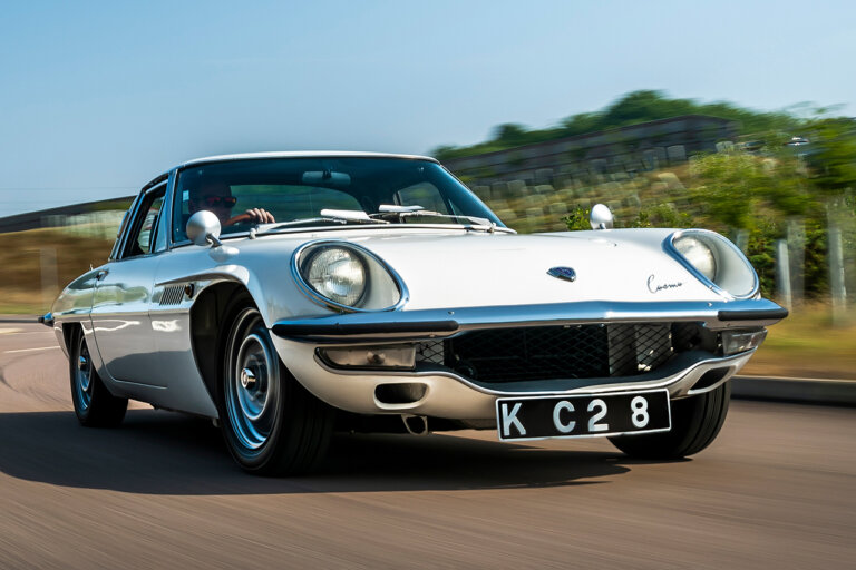 White Mazda car with an driving it on a freeway with blue sky and mountains