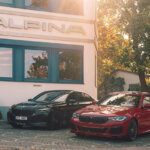 two bmw cars one blue one red next to each other in front of a store that says Alpina above it