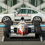 white Porsche F1 race car in front of a white 911 porsche