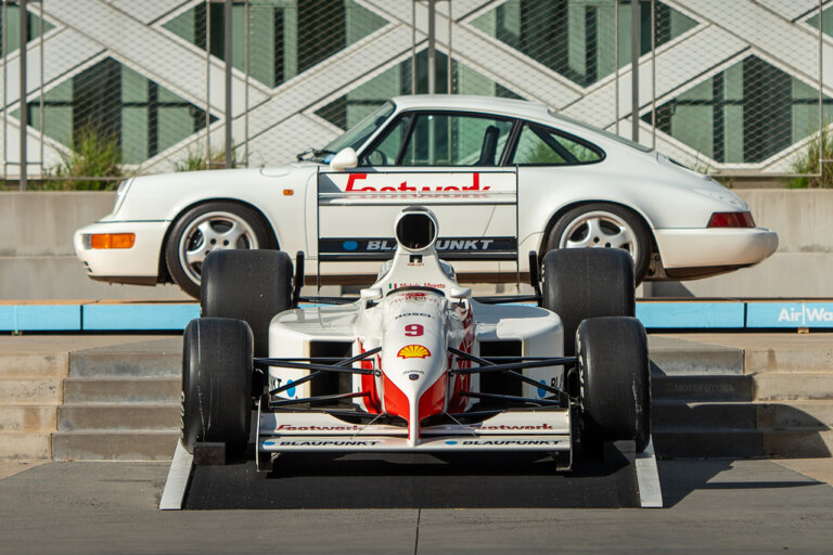 white Porsche F1 race car in front of a white 911 porsche