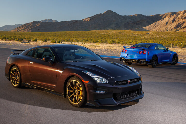 two Nissan GT-R R35's parked next to one another on a racetrack