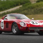 Red Ferrari 250 GTO parked on ground with grassy hill in background