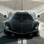 Black with single orange stripe of a Koenigsegg car on the ground with a painted x on the ground