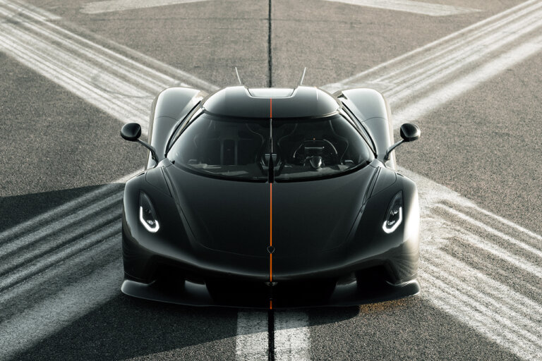 Black with single orange stripe of a Koenigsegg car on the ground with a painted x on the ground