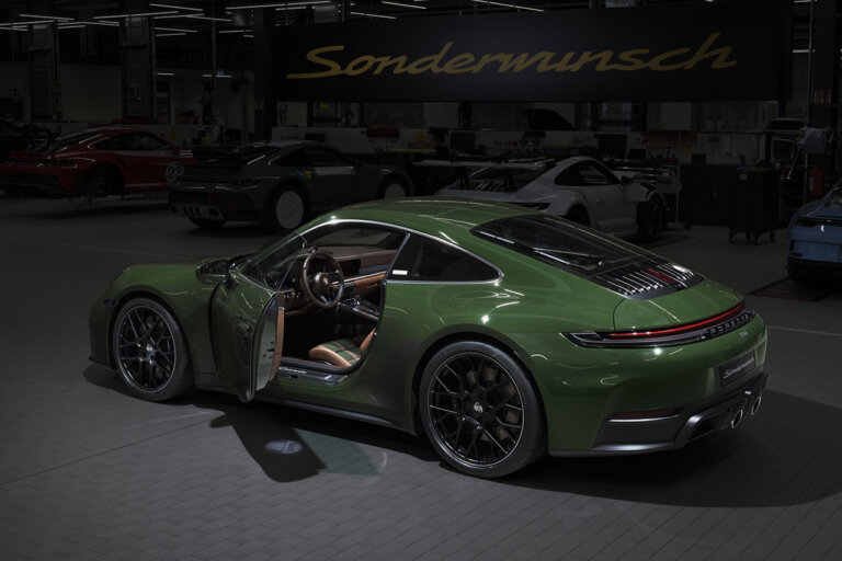 Green Porsche 911 pictured in a dark room with a sign above it
