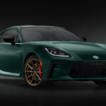 Green Toyota GR86 parked in a dark room with a black background