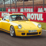 Yellow 911 RUF CTR driven by a man on a racetrack with words behind it saying MOTUL in all white
