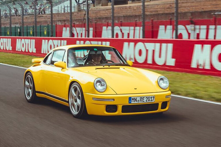 Yellow 911 RUF CTR driven by a man on a racetrack with words behind it saying MOTUL in all white