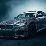 Silver and black BMW with grid lines on the front of the car and smoke behind the car