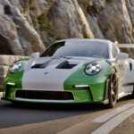 white and green Porsche 911 GT3 RS driving on a road next to a cliffside