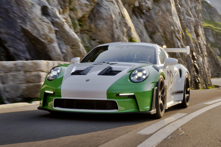 white and green Porsche 911 GT3 RS driving on a road next to a cliffside
