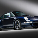 Blue Porsche 911 turbo parked in a dark room with a white stripe on a black background