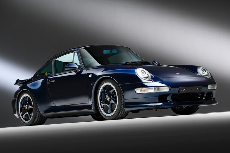 Blue Porsche 911 turbo parked in a dark room with a white stripe on a black background
