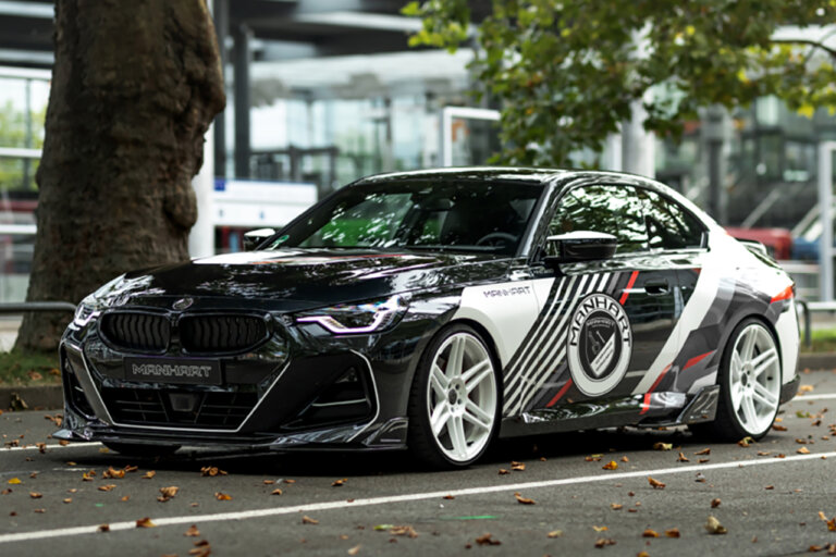 Black with red and white accents of a BMW m240i parked under a tree with leaves on the ground