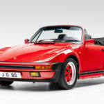 red Porsche 911 turbo cabriolet with black leather top down positioned in a white room