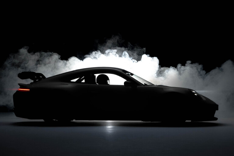 Porsche 911 992.2 car silhouette shot in a dark room with smoke behind it and a driver in the drivers seat