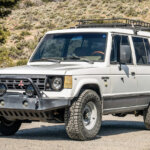 White Gen 2 Mitsubishi Pajero parked in front of a hill side