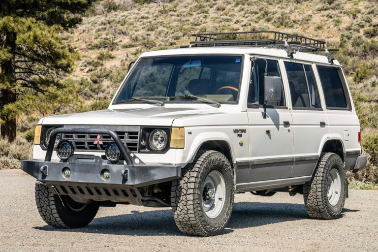 White Gen 2 Mitsubishi Pajero parked in front of a hill side