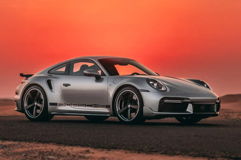Silver Porsche 911 Turbo parked on a road with orange sunset in the background