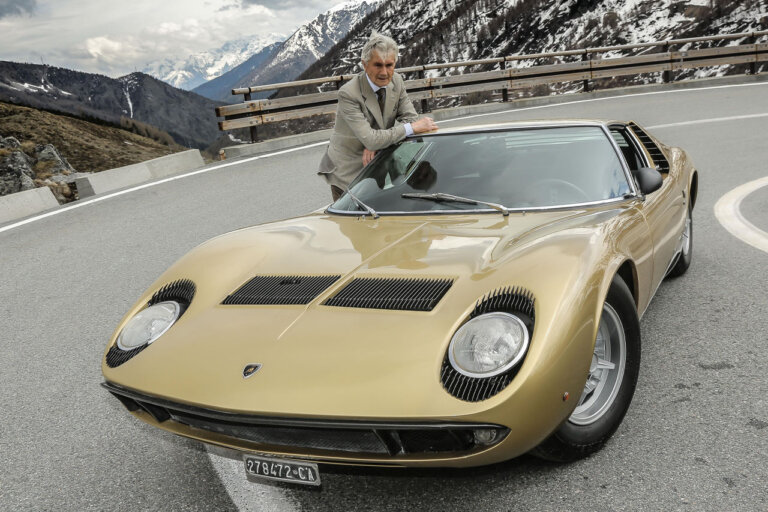 marcello gandini with a gold lamborghini miura on a mountain road
