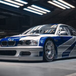 Need For Speed Most Wanted BMW M3 GTR with the silver and blue livery shot in a garage with rows of lights above the car shining down on it.