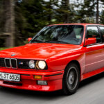 red bmw e30 m3 on a forest road