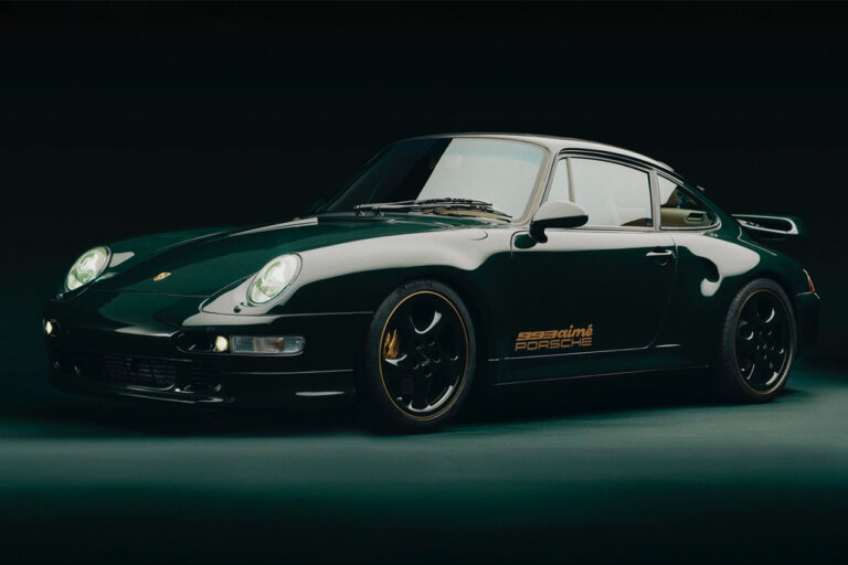 Green Aimé Leon Dore Porsche 993 car pictured in a dark room with a spotlight above the car.