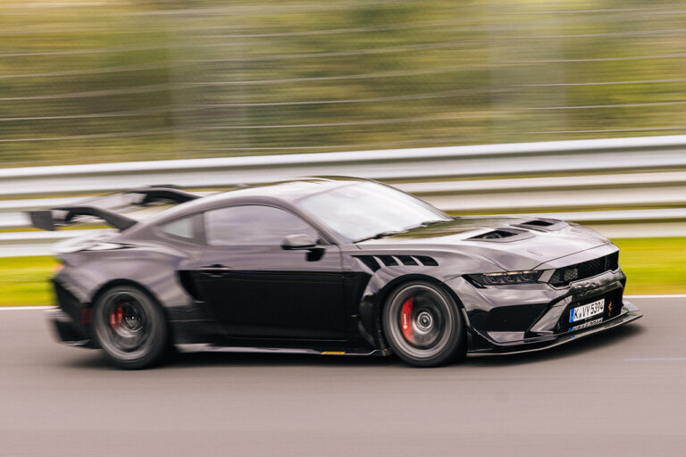 Black 2025 Ford Mustang GTD flying by on the Nürburgring race track.
